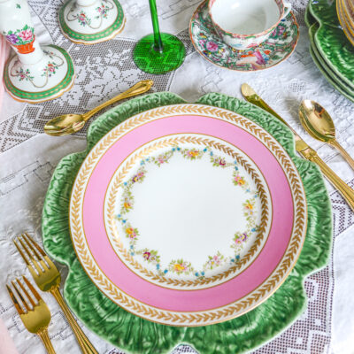 Ovington Bros. pink floral swag Limoges dinner plates on top of green cabbage ware charger in pink and green table setting