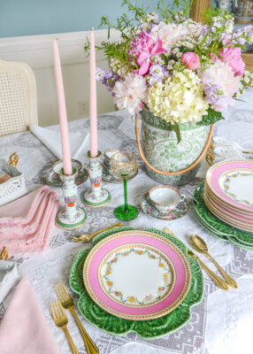 A pink and green tablescape with rococo inspired florals, Limoges plates, cabbage ware, and pink peonies