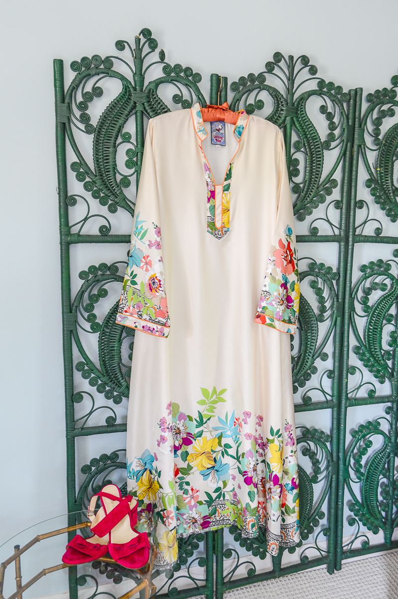 Johnny Was silk floral caftan for wedding guest dress, hung on green wicker screen