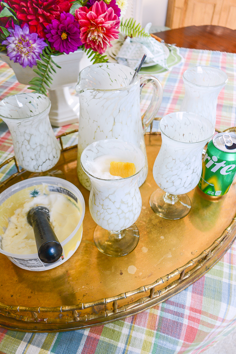 Pineapple sherbet limeade mocktail in white spotted glasses served on brass tray