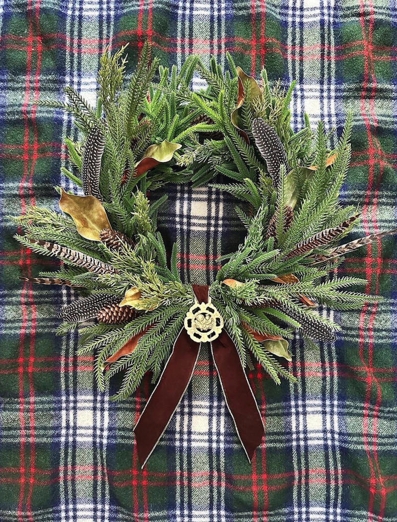 evergreen wreath with brown bow and horse brass for fall inspiration