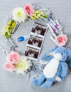 Our IVF Journey: a wreath of flowers, syringes, and blue bunny toy surrounding our precious baby pictured on ultrasound