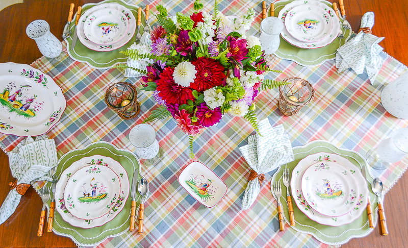 A fall tablescape with plaid tablecloth, French faience dishes, and dahlia centerpiece