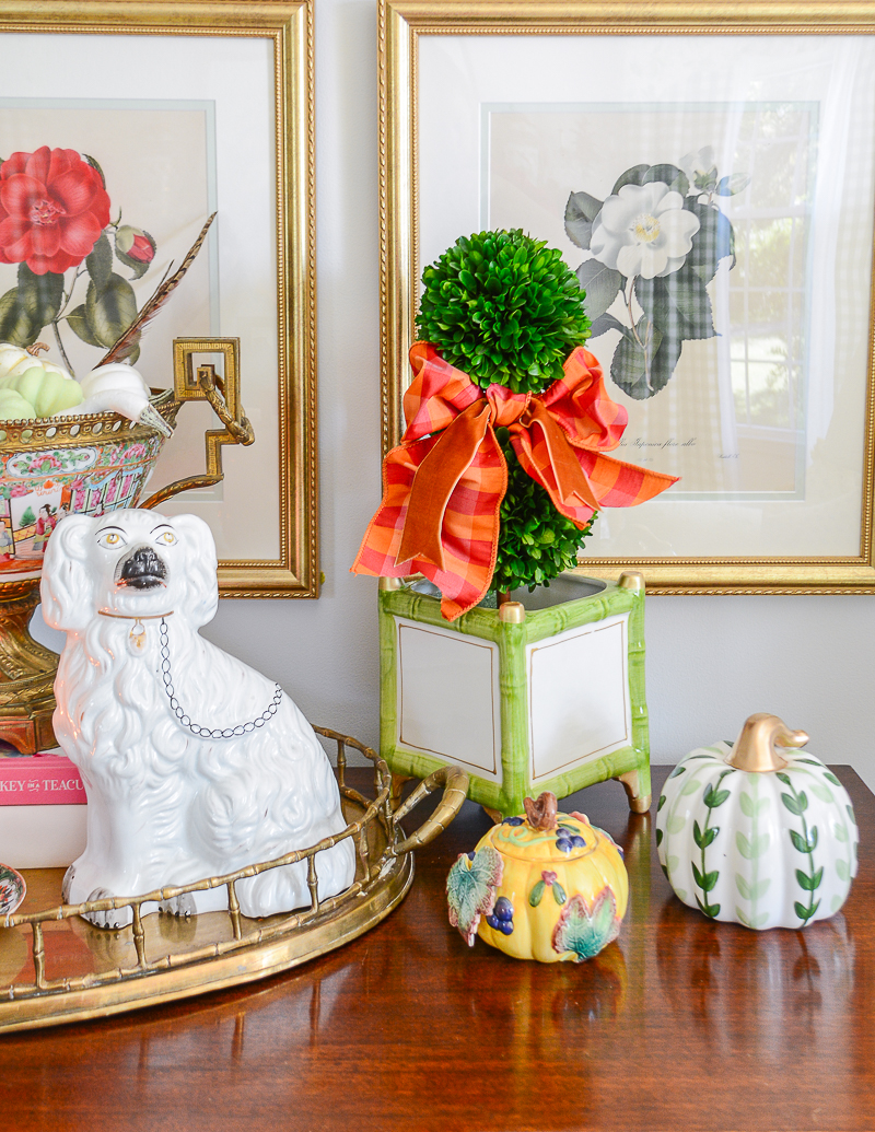 A boxwood topiary with pink and orange gingham bow for fall living room decor