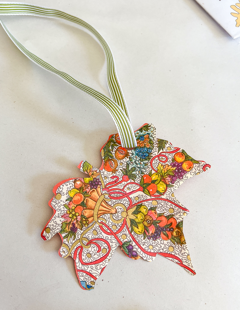 Punch a hole in the leaf corner and thread ribbon through hole. Tie a bow at top of ribbon to hang on tree.