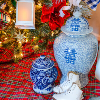 A red tartan tree skirt, blue and white Chinese porcelain temple jars and a pair of white ice skates decorate the bottom of the Christmas tree.