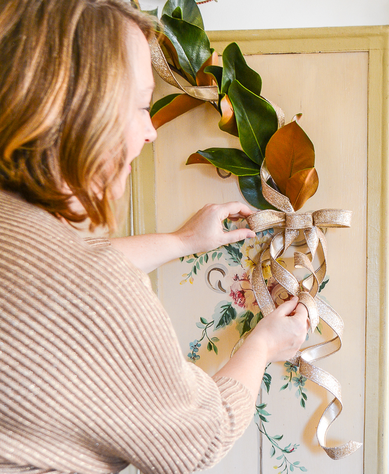 Katherine fixes glitter ribbon bow on magnolia garland