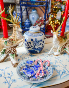 Preppy Chinoiserie Christmas decor on the coffee table featuring Fitz & Floyd reindeer candleholders, blue and white peony ginger jar, and a dish of candy