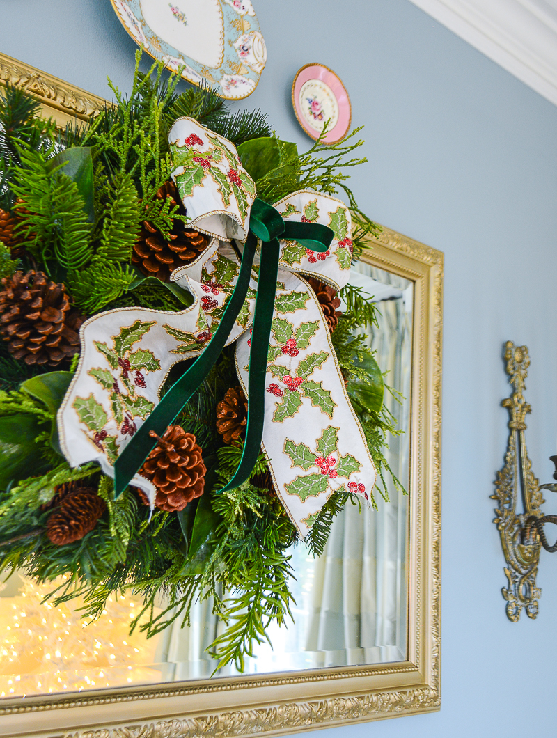 pine wreath with holly and velvet bow hung on mirror