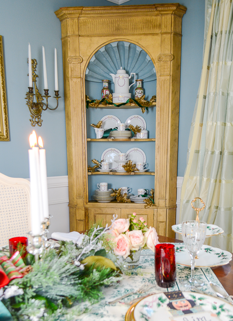 Corner hutch decorated with Furstenberg Carolina dessert service, gold holly leaves, and green ribbon