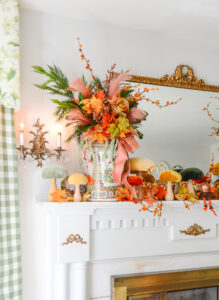 A magical autumn mantel arrangement with velvet mushrooms, Rose Medallion, fall leaves, bittersweet, and whimsical elves