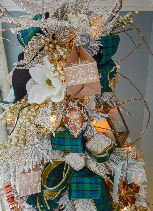 top of gingerbread forest Christmas tree with gingerbread houses, magnolia, black watch plaid ribbon, and iced branches