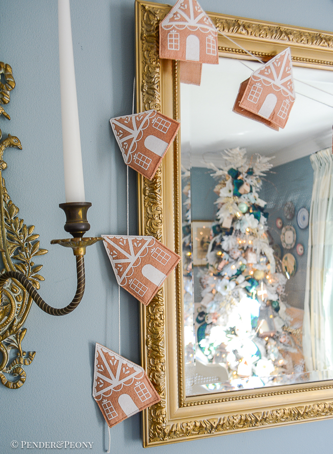 felt gingerbread house garland hangs on mirror