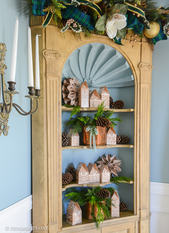 The gingerbread forest Christmas theme continues in the hutch with gingerbread house advent calendar, antique copper, cedar, and paper snowflakes