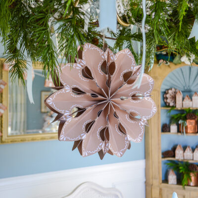 Gingerbread paper snowflake hangs from chandelier