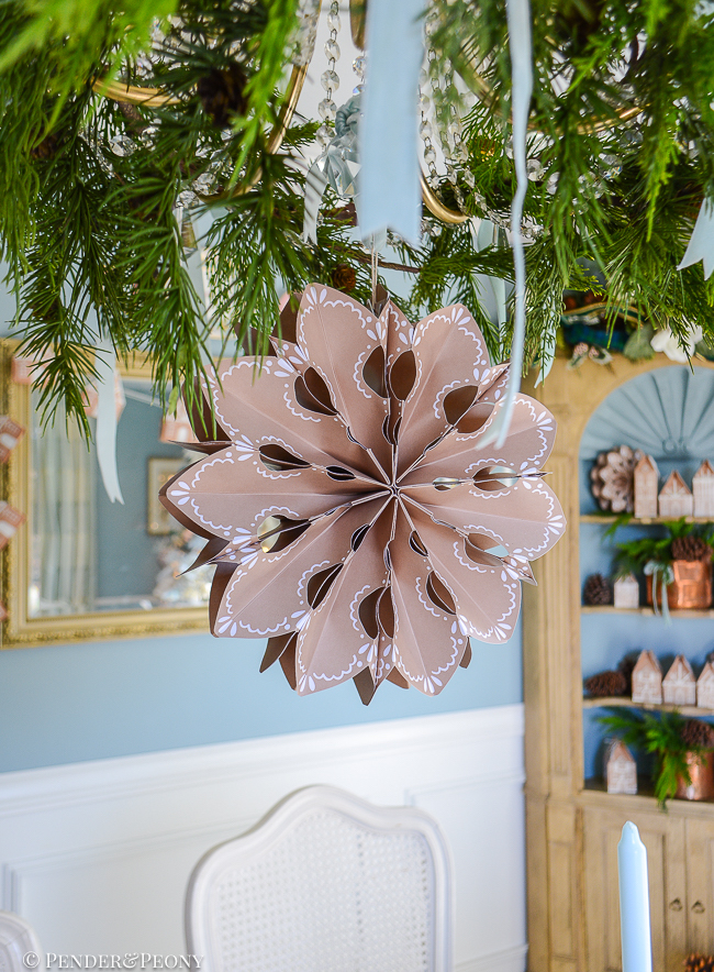 Gingerbread paper snowflake hangs from chandelier