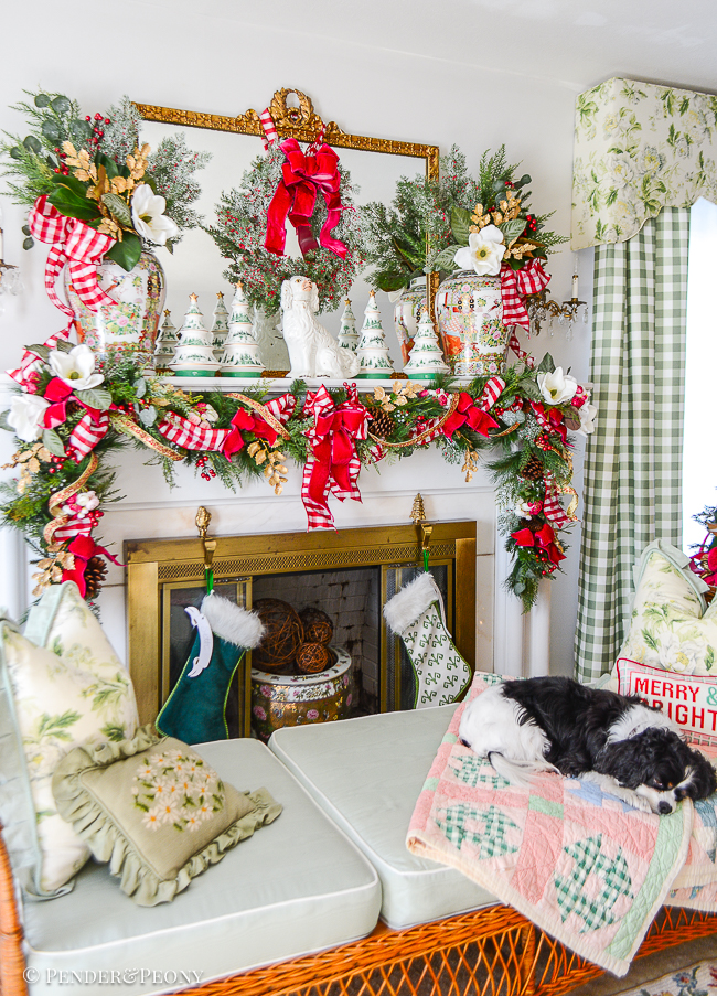 Henry sleeps on the daybed in front of the mantel decorated with pink velvet, red and white gingham ribbons; magnolia; Rose Medallion, and a Jolly Blossoms garland