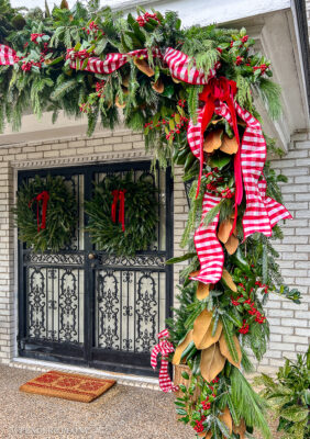 A DIY fresh evergreen garland hung over the front porch roof and columns