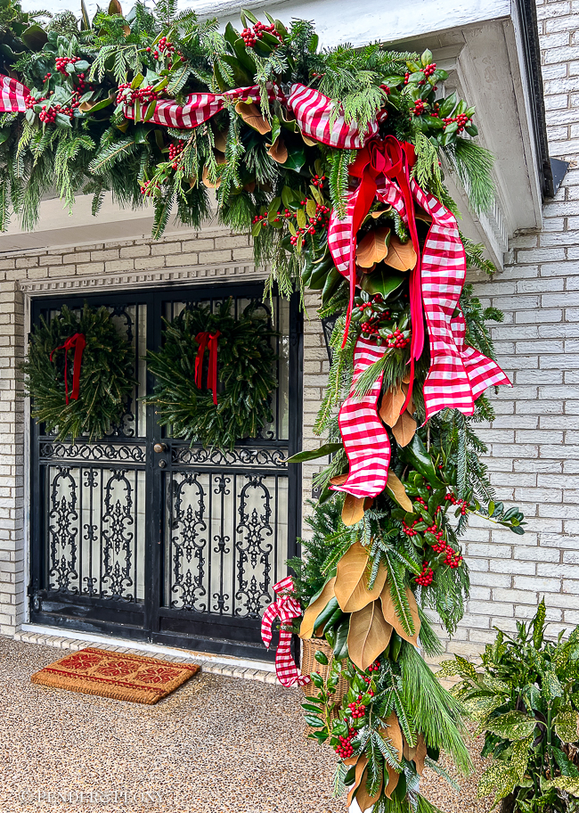 A DIY fresh evergreen garland hung over the front porch roof and columns