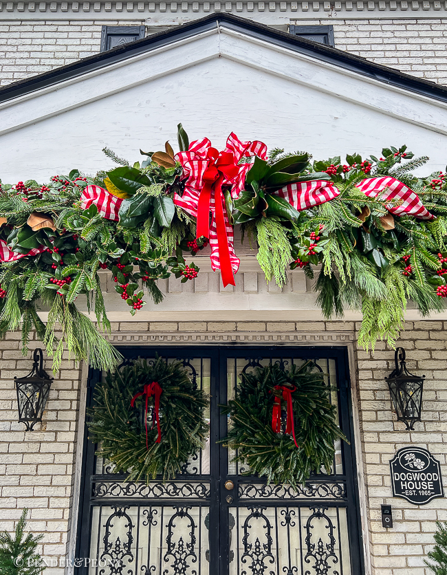 A DIY fresh evergreen garland hung over the front porch roof and columns