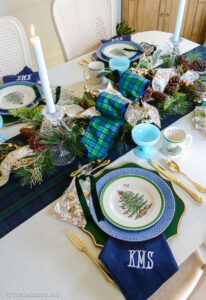 A traditional Christmas tablescape with Black Watch tartan linens, evergreen centerpiece, Spode Christmas china, and gingerbread cookies