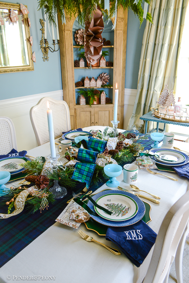 Black Watch tartan table runner layered with evergreen centerpiece, Blue Mottahedeh china, Spode Christmas tree china, and gingerbread cookies for a classic Christmas table idea