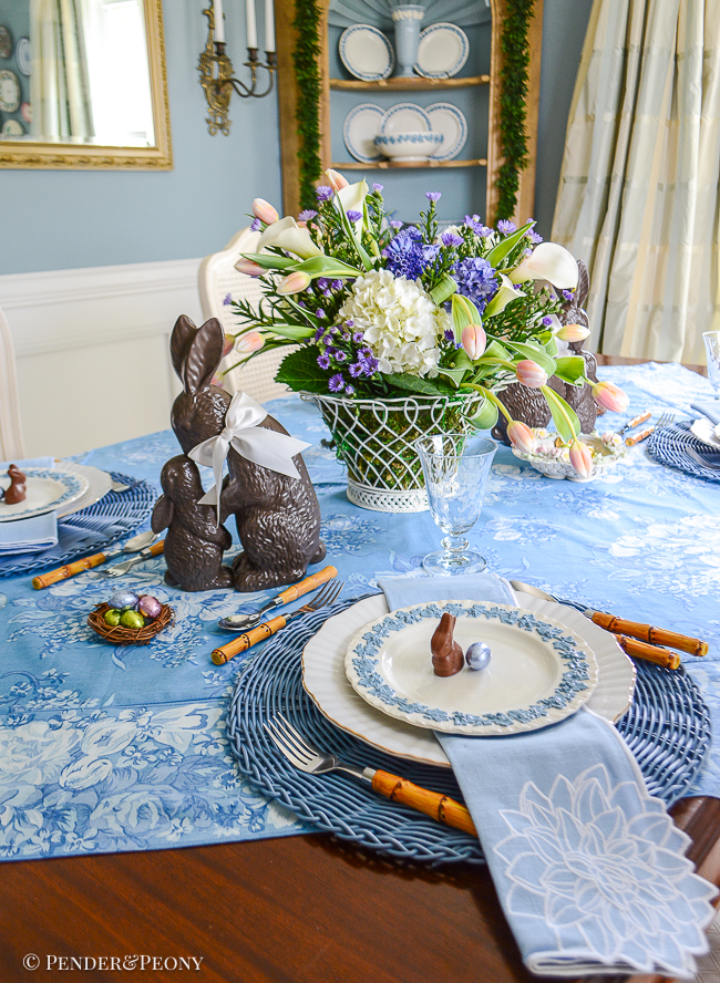 A blue and white Easter tablescape with chocolate bunnies, Wedgwood Queensware, and chintz linens