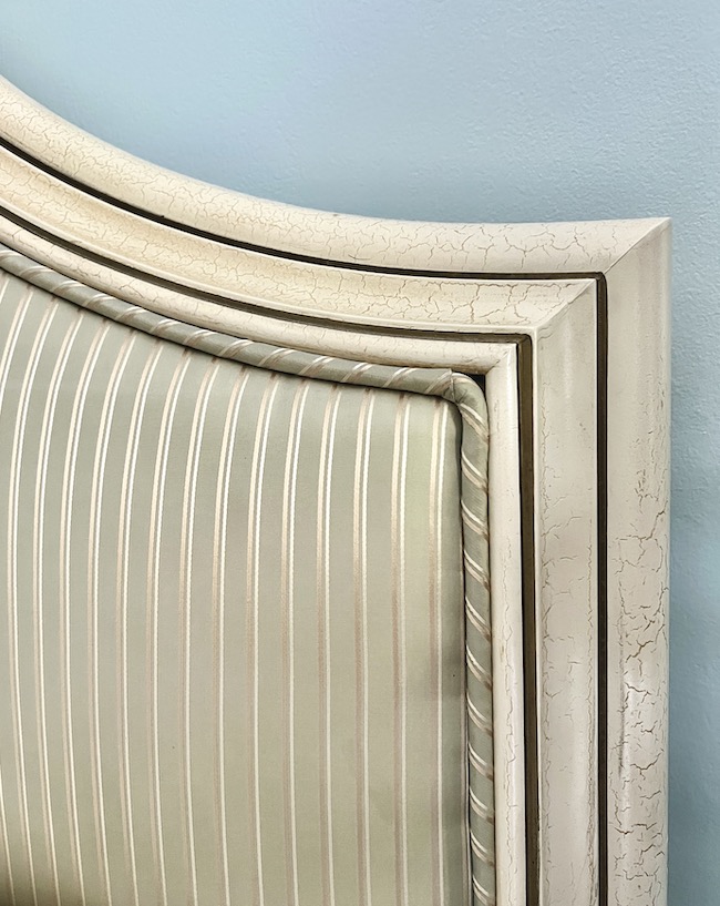 Master bedroom headboard upholstered in a green and tan silk stripe