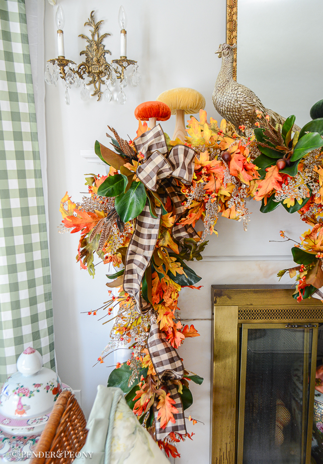 Glittered pheasant statue perches on mantel for autumn decor surrounded by velvet mushrooms and fall garland of oak, magnolia, bittersweet, and fern.