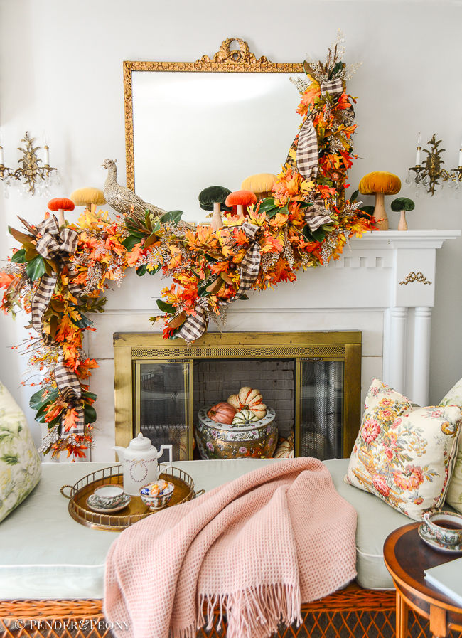 Glittered pheasant statue perches on mantel for autumn decor surrounded by velvet mushrooms and fall garland of oak, magnolia, bittersweet, and fern.
