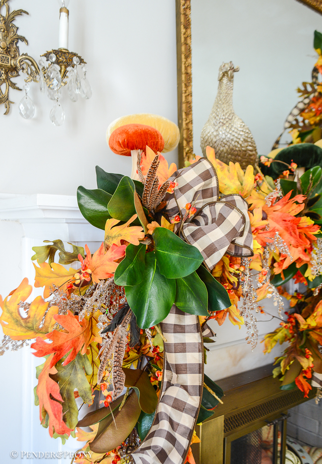 A close up view of the fall mantel garland made from oak leaves, bittersweet, magnolia, brown and white gingham ribbon, and glittered fern