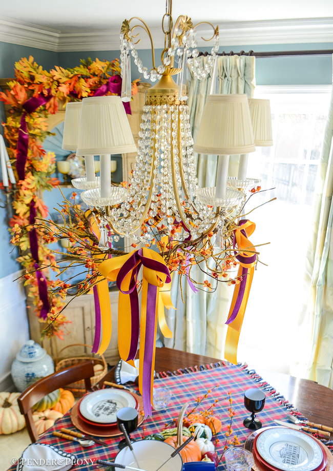 Antique French crystal chandelier with bittersweet garland and bows decorated for fall dinner party