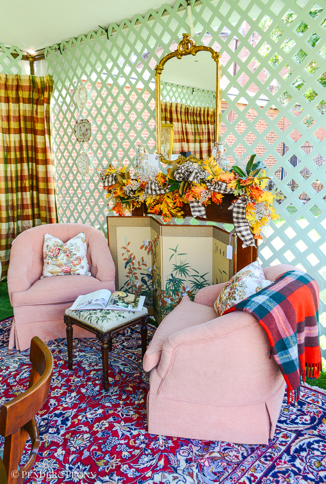 Two pink chairs flank a fireplace mantel with gold mirror above