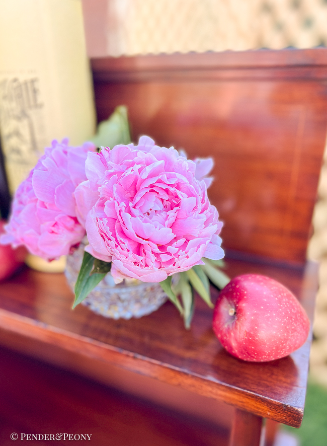 Pink peonies in crystal vase with apple
