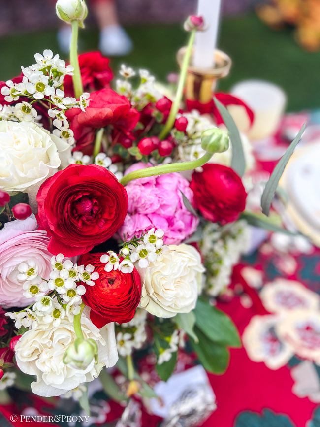 Red ranunculus, white roses, and pink peonies in a Christmas centerpiece