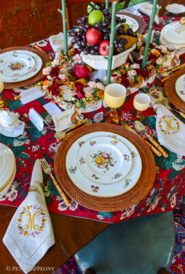 A red chintz tablecloth, hand painted fruit china, Murano goblets, Limoges porcelain, monogrammed napkins, and a surtout de table layer this elegant Thanksgiving tablescape