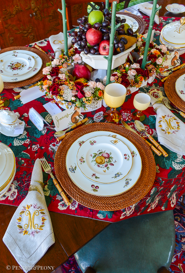 A red chintz tablecloth, hand painted fruit china, Murano goblets, Limoges porcelain, monogrammed napkins, and a surtout de table layer this elegant Thanksgiving tablescape
