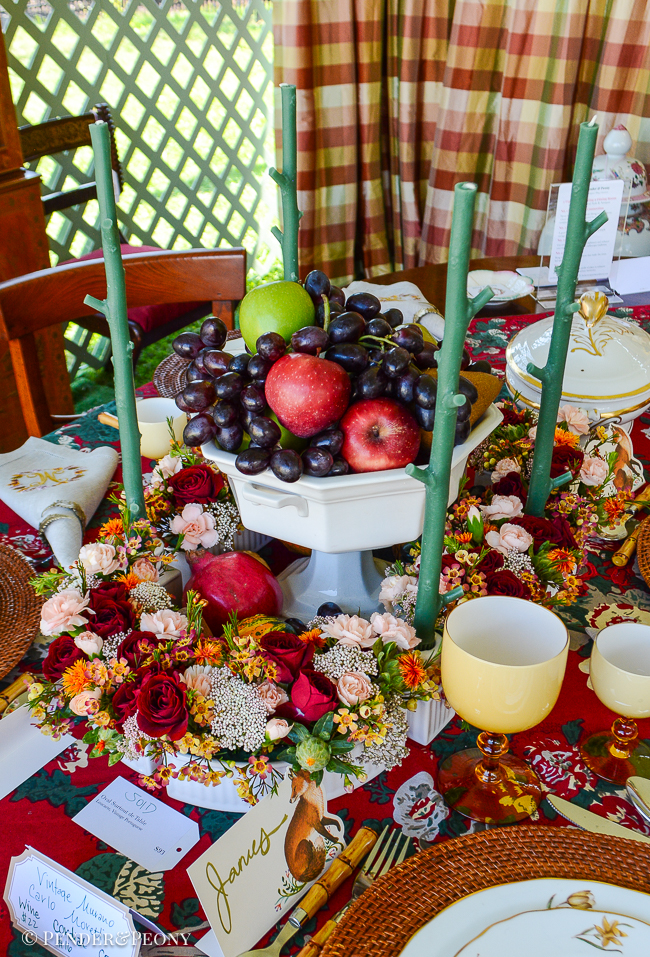 Thanksgiving centerpiece idea with ironstone compote filled with fruit surrounded by a surtout de table with flowers and stick candles