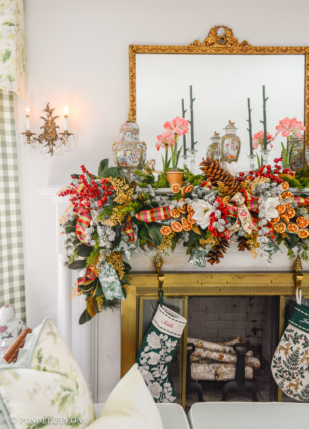 A Grand Botanical Christmas mantel decoration with DIY garland made of magnolia, pine, cedar, red berries, gold fern, orange slices, ribbon, and amaryllis.