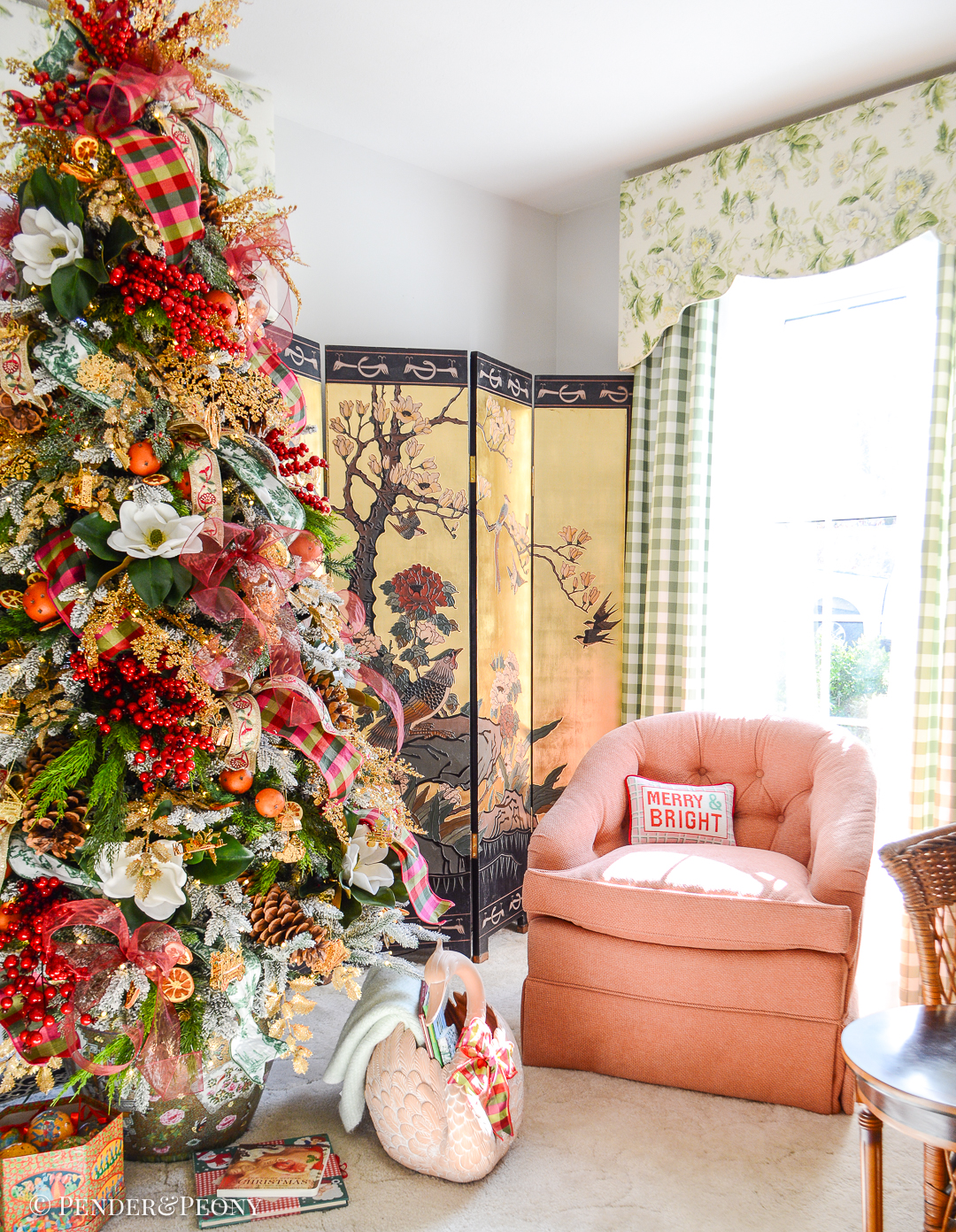 Pink chair beside Christmas tree with "Merry and Bright" needlepoint pillow