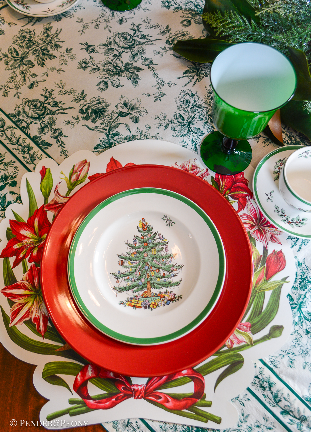 Green, white, and red Christmas table set with Spode's Christmas tree plates, amaryllis placemats from Hester & Cook, and vintage beaded fruit