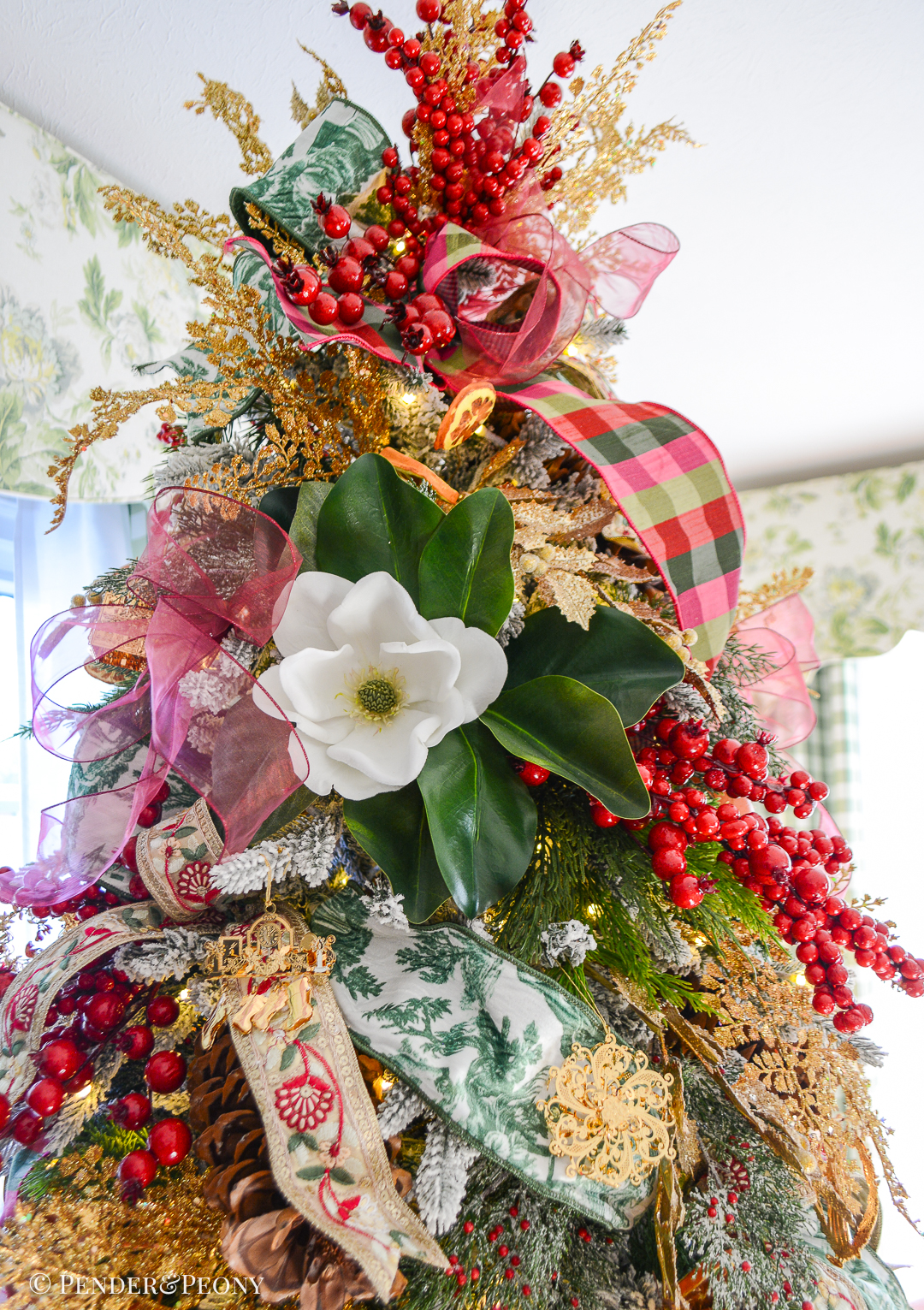 A detailed view of the topper on the botanical themed pink, red, green Christmas tree