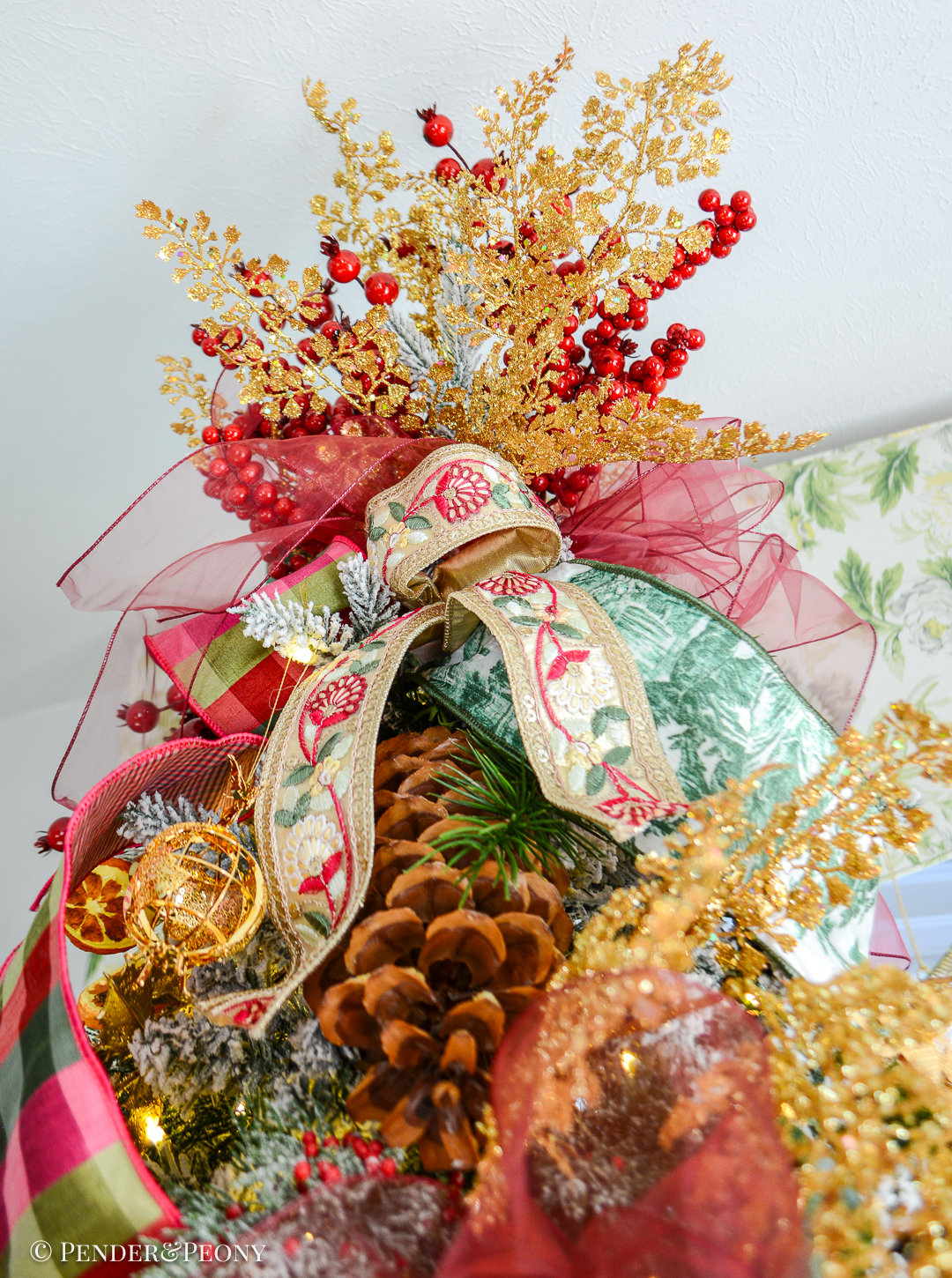 Top of Grand Botanical Christmas tree with ribbon tuft, organza bow, gold fern, and red berries