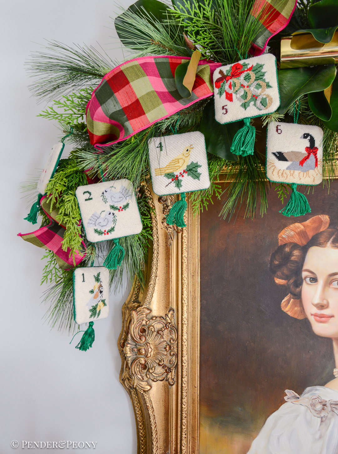 Vintage needlepoint 12 days of Christmas ornaments hung on evergreen magnolia swag above portrait