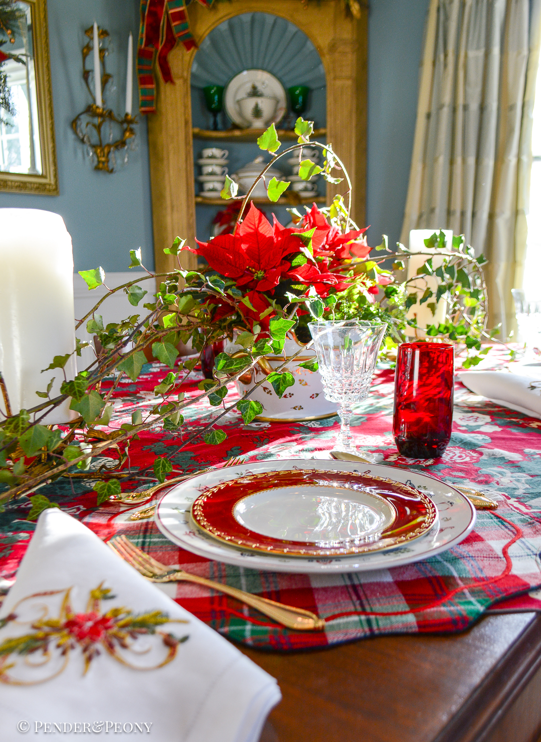 The Christmas table centerpiece with red poinsettia, fern, and ivy in a gilt porcelain cachepot