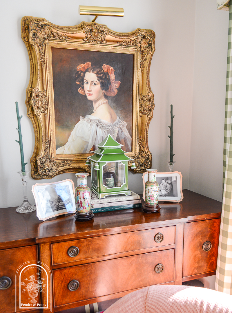 A collection of storied decor adorn's this antique sideboard with a portrait, Rose Medallion, family photos, pagoda lantern, and design books. 