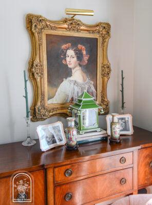 Sideboard display with portrait and lantern arranged symmetrically to combat cluttered feel