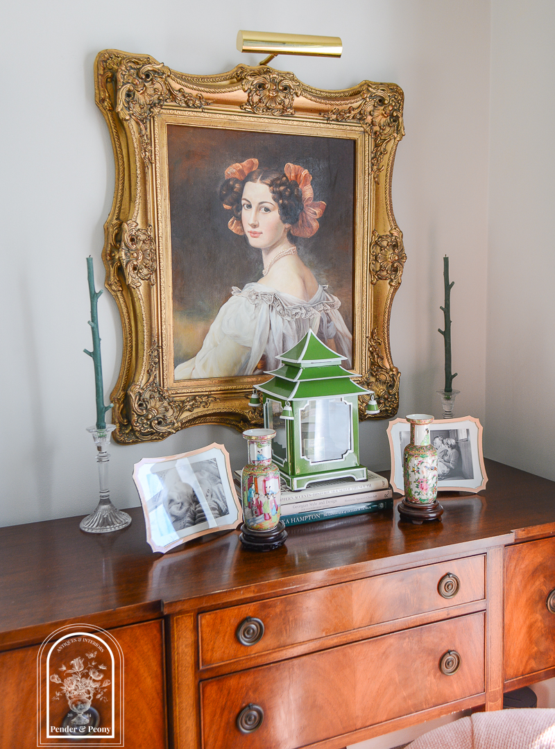 Sideboard display with portrait and lantern arranged symmetrically to combat cluttered feel