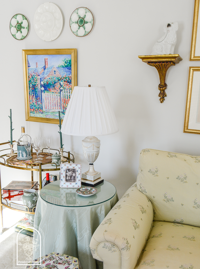 Skirted end table in living room with lamp, photo, and dish
