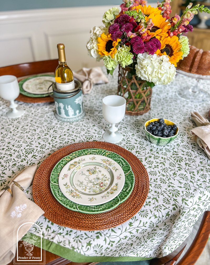 A green and white summer table with Royal Doulton china, cabbageware, linen napkins, Indian block print tablecloth, white Portieux Vallerysthal goblets, and sunflowers